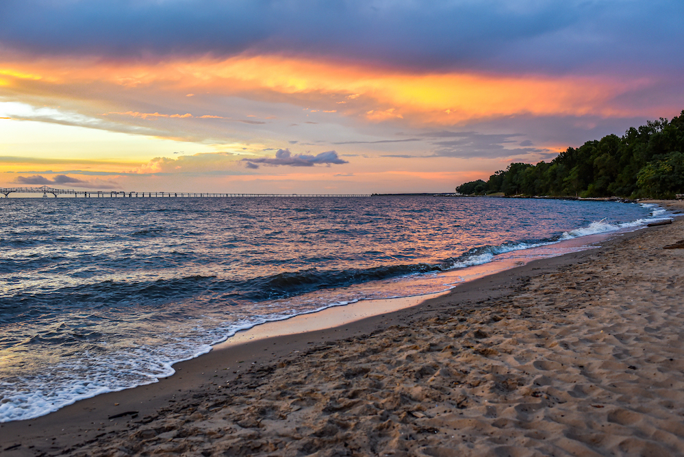 chesapeake bay beach at sunset with bridge in background