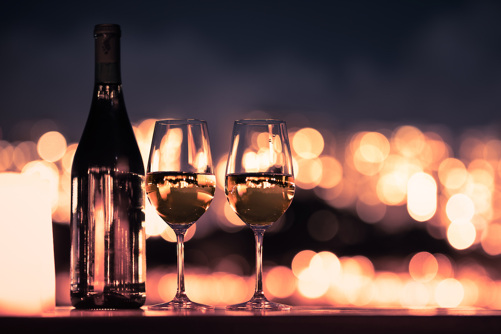 two glasses of wine and the bottle at a romantic dimly lit setting