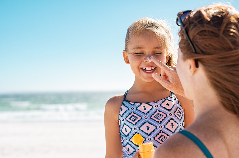 mother putting sunscreen on young daughter