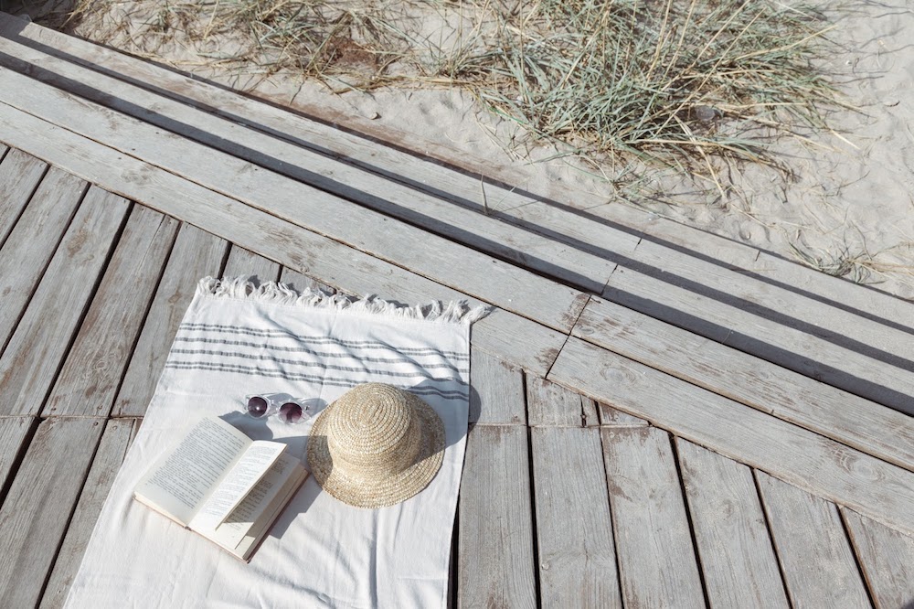 towel by beach with hat and sunglasses on it